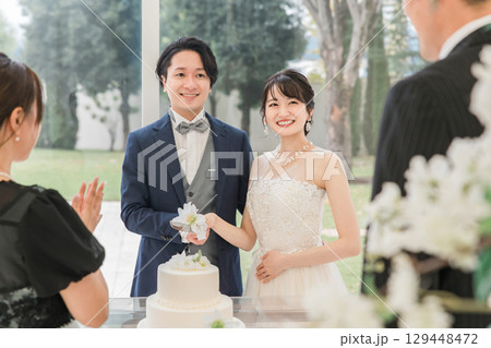 結婚式でケーキ入刀をする新郎新婦とゲスト(ウェディングケーキ・ケーキ入刀) 129448472