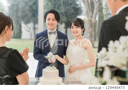結婚式でケーキ入刀をする新郎新婦とゲスト(ウェディングケーキ・ケーキ入刀) 129448473
