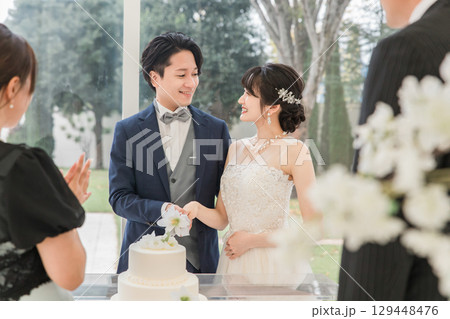 結婚式でケーキ入刀をする新郎新婦とゲスト(ウェディングケーキ・ケーキ入刀) 129448476