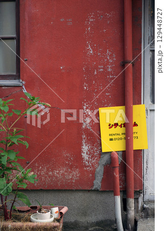古い木造アパートの赤い壁 129448727