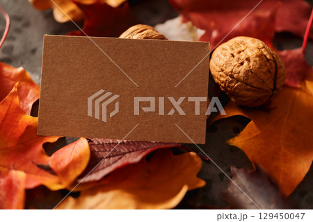 Autumn theme background with leaves over concrete with brown paper card Autumn theme background with leaves over concrete with brown paper card 129450047