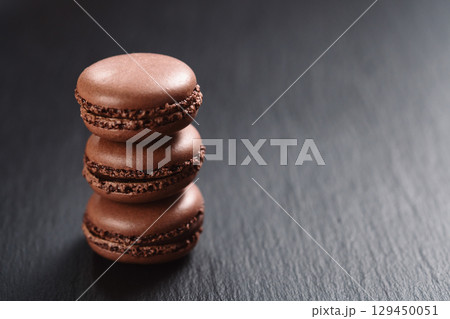 Chocolate macarons stacked on slate board with copy space 129450051