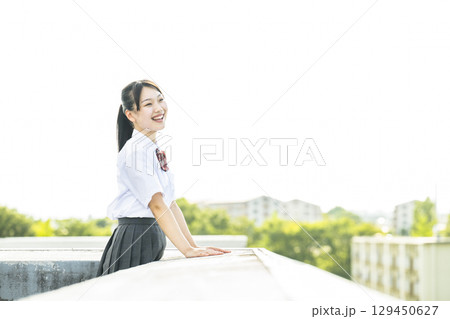 学校の屋上から景色を見る女子高生 129450627