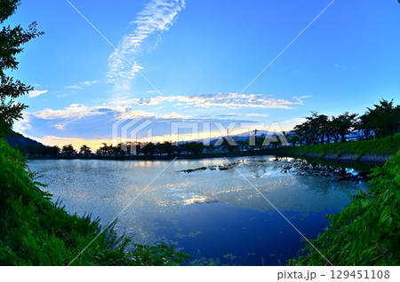 日の出前の青空と朝焼けの空を映す溜池の水面 日の出前の青空と朝焼けの空を映す溜池の水面 129451108