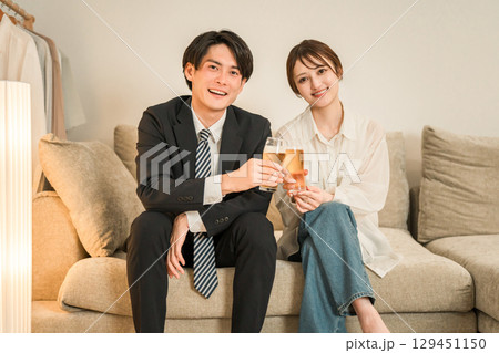 夜,帰宅後にソファに座りながらビールを飲む若いアジア人夫婦,カップル 129451150