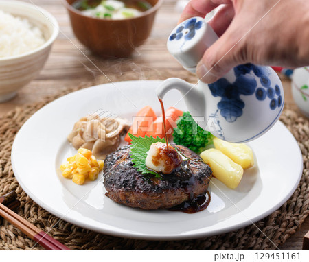 湯気立つ和風おろしハンバーグと彩り野菜の定食　温かい家庭料理やレストランメニューに最適 129451161