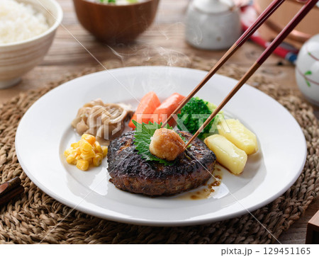 湯気立つ和風おろしハンバーグと彩り野菜の定食　温かい家庭料理やレストランメニューに最適 129451165