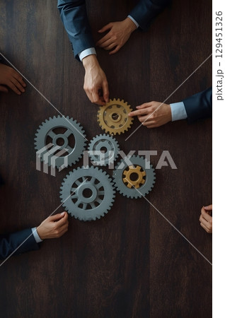 Top-Down View of Wooden Table with Interlocking Gears and Business Hands  Teamwork Concept Illustration Top-Down View of Wooden Table with Interlocking Gears and Business Hands  Teamwork Concept Illustration 129451326