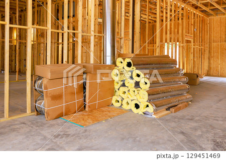 Unfinished space features stacked insulation rolls, awaiting installation in residential construction site. 129451469
