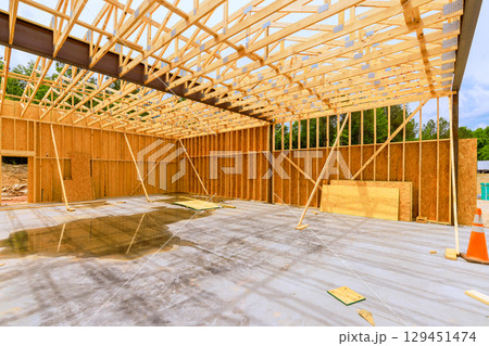 Workers have framed new structure while rain shower creates puddles on concrete surface. 129451474