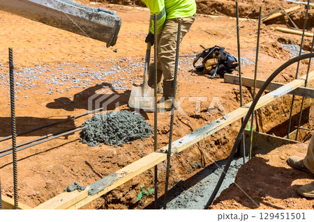 Workers are actively pouring concrete excavating soil at construction site under works day time 129451501