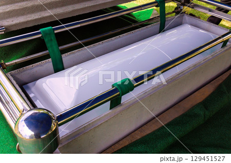 White casket in metal frame is surrounded by green fabric at an outdoor memorial in tranquil cemetery White casket in metal frame is surrounded by green fabric at an outdoor memorial in tranquil cemetery 129451527