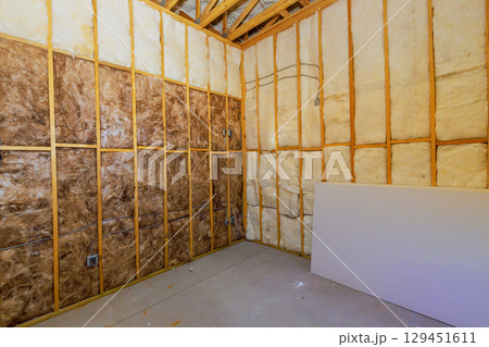 Construction work shows bare room with insulation framed walls, indicating an ongoing renovation project. 129451611