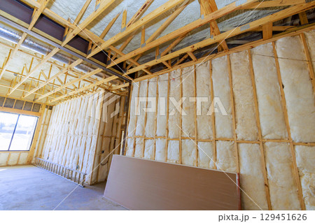 Interior framing, insulation work is underway in residential construction setting during works time hours. 129451626