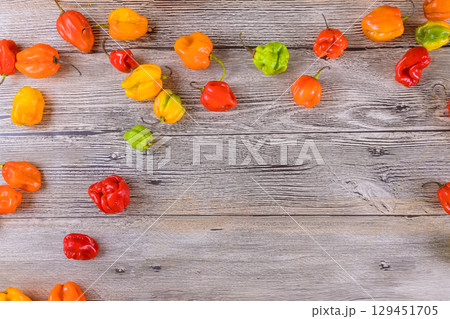 Vibrant habanero peppers display unique shapes on rustic wooden background. 129451705