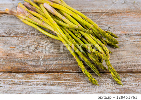 Fresh harvested organic green asparagus spears arranged on weathered wooden table 129451763