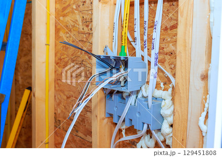 Electric wires are being connected in new home framing, installation process construction tools. Electric wires are being connected in new home framing, installation process construction tools. 129451808