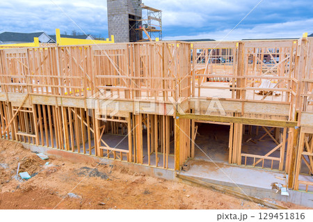 Wooden beams frames rise on construction site in residential area under suburban location construction ongoing development. Wooden beams frames rise on construction site in residential area under suburban location construction ongoing development. 129451816