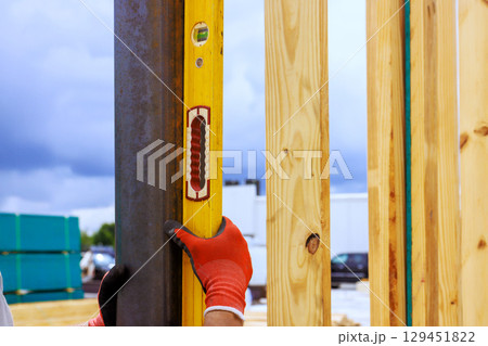 Worker checks alignment of steel column beams using level tool at construction site during work time Worker checks alignment of steel column beams using level tool at construction site during work time 129451822