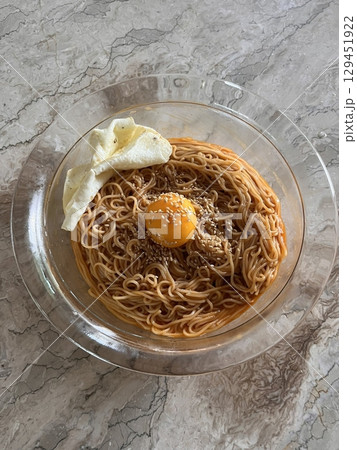 Bibimyeon, a flavorful Korean dish featuring cold noodles tossed in a spicy, tangy sauce, topped with fresh vegetables and a boiled egg. Perfect for summer meals, showcasing vibrant flavors and colors 129451922