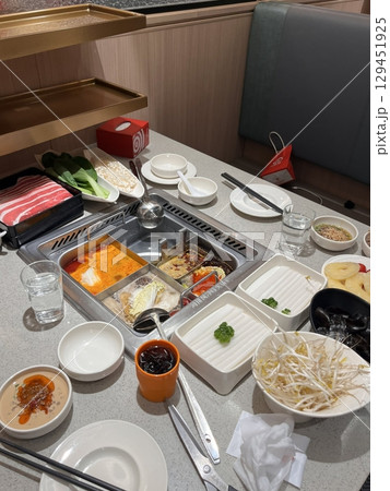 A bubbling hotpot with rich broth, tender meats, fresh vegetables, and noodles simmered to perfection. Ideal for a communal meal bursting with bold, hearty flavors. 129451925
