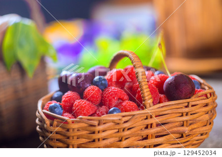 Wicker basket filled with vibrant red blue berries showcases summer bounty at bustling market. 129452034