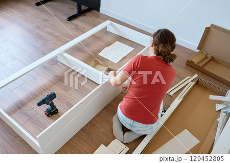 Woman assembling furniture at home 129452805