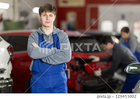 Service station young man employee works in repair box, department Service station young man employee works in repair box, department 129453002