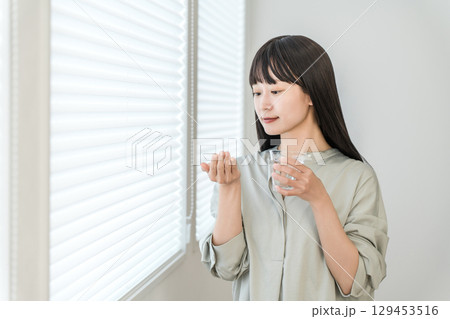 服薬・薬を飲む頭痛・体調不良のアジア人女性 129453516