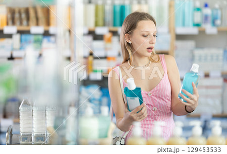 Blonde woman holding mouthwashes in her hands 129453533