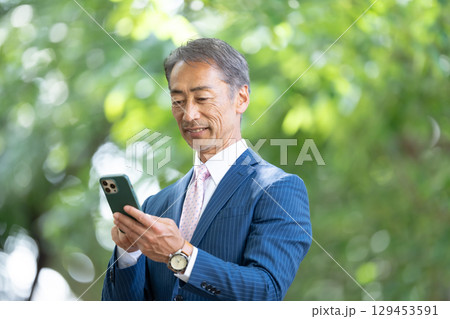 ビジネスマン　ポートレート　新緑　スマホ　 129453591