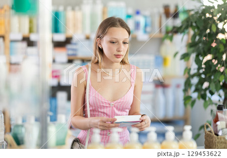 Young woman chooses pills at pharmacy Young woman chooses pills at pharmacy 129453622