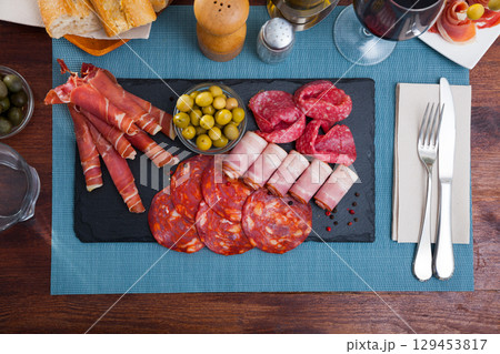 Top view of sliced gammon, chorizo, salami, bacon on slate board 129453817