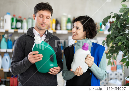 Female saleswoman offers man buy a detergent in supermarket Female saleswoman offers man buy a detergent in supermarket 129454097