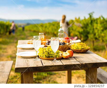 AI generated Chilled grape juice in glass pitcher with fresh grapes and halves on rustic table Sunny vineyard background with farmers harvesting Perfect for healthy drinks wine and agriculture themes 129454237