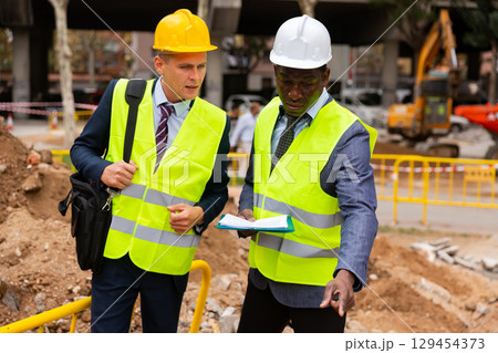 Engineers discussing road mending outdoors Engineers discussing road mending outdoors 129454373