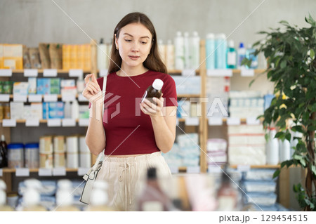 woman chooses a medicinal syrup in a pharmacy woman chooses a medicinal syrup in a pharmacy 129454515