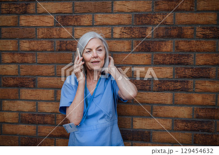 Older nurse resting during long hospital shift, making phone call Older nurse resting during long hospital shift, making phone call 129454632