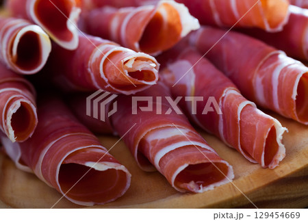 Spanish dry cured jamon on wooden plate 129454669