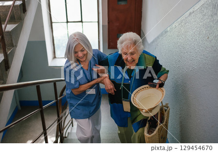Female healthcare worker helping senior patient walking up the stairs. Female healthcare worker helping senior patient walking up the stairs. 129454670