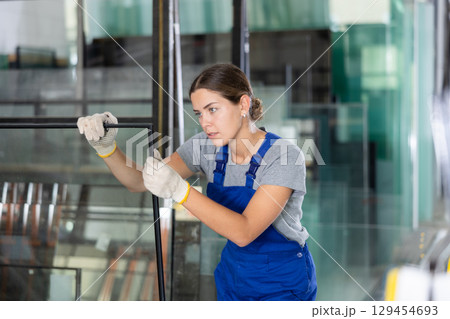 Female worker inspecting insulated glass units in production workshop Female worker inspecting insulated glass units in production workshop 129454693