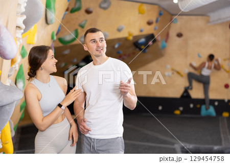 Young man and woman talking near climbing wall 129454758