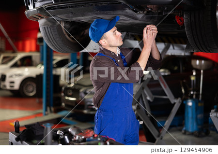 Young mechanic guy fixes car wiring Young mechanic guy fixes car wiring 129454906