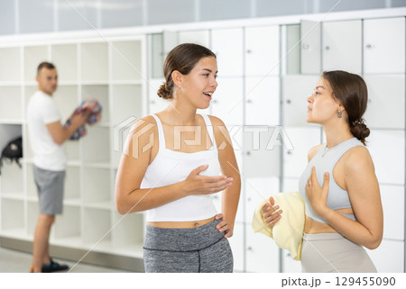Two young women talking in locker room 129455090