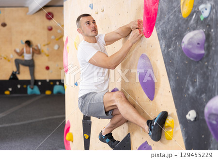 Young man practicing rock climbing on climbing wall 129455229