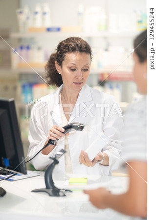 Adult female pharmacist punches medicine at cash register 129455244