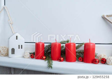 New year and Christmas preparation. Four red advent candles in white windowsill. Handmade eco-friendly decor. Sustainable Christmas decoration 129455258