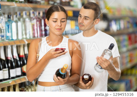 Spouses buyers scan QR code on label of alcohol drinks 129455316