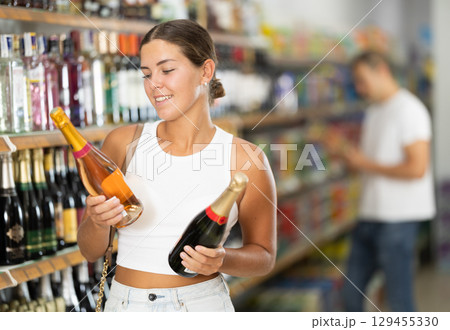 Woman chooses bottle of champagne in shop store 129455330
