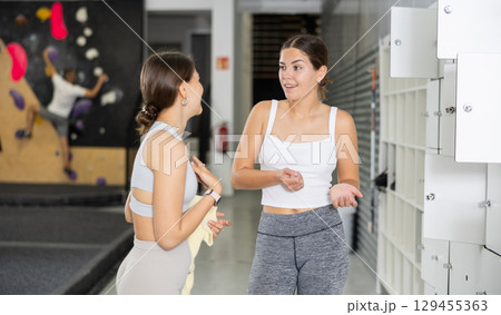 Two young women talking in locker room 129455363